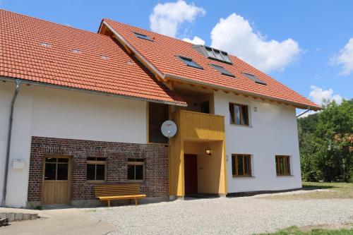 ein weißes Gebäude mit orangefarbenem Dach und einer Bank in der Unterkunft WaldBlick im Happy Allgäu - Wohnung mit großer Dachterrasse in Leutkirch im Allgäu