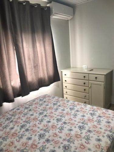 a bedroom with a bed and a dresser and a window at Casa com 2 quartos agradáveis com ar condicionado in Foz do Iguaçu