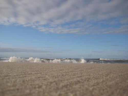 a sandy beach with waves in the ocean at Hotel Leegerpark in Greetsiel