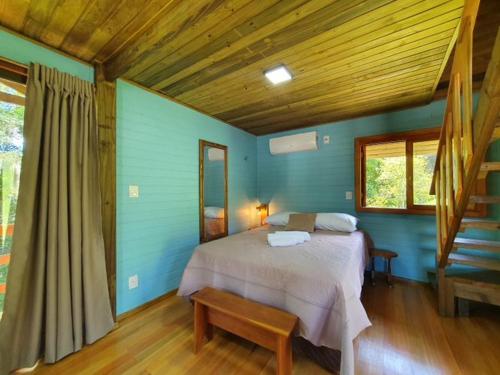 a bedroom with blue walls and a bed with a bench at Chalés Da Cascata - Cereja in Gramado