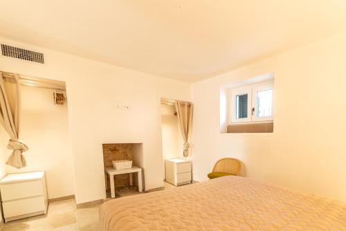 a white bedroom with a bed and a fireplace at DIMORA PALASCIANO in Alberobello