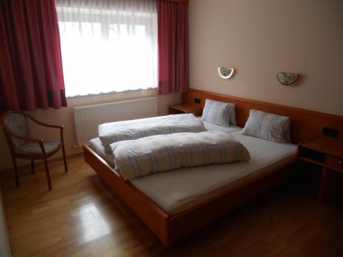 a bedroom with a bed and a chair and a window at Appartement beim Brunnen 12 in Sölden