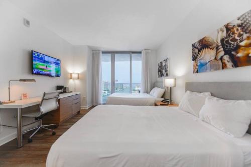 a hotel room with a bed and a desk and a computer at Wonderful Studio Beachwalk with Great Views in Hallandale Beach
