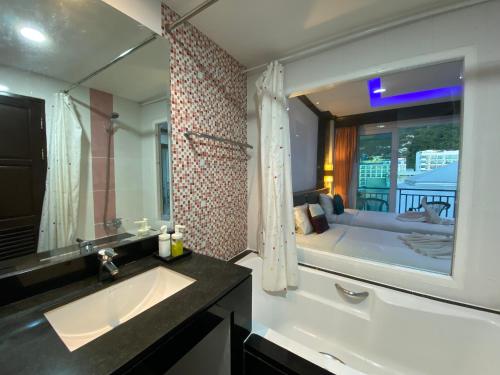 ein Badezimmer mit einem Waschbecken und einem großen Spiegel in der Unterkunft 77 Patong Hotel & Spa in Patong Beach