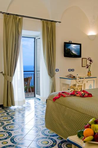 a bedroom with a bed and a tv and a balcony at Hotel Margherita in Praiano
