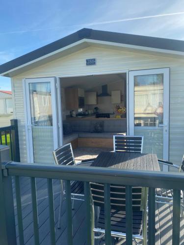 a screened in porch with a table and chairs on a deck at Modern 3 bedroom caravan near the beach in Walton-on-the-Naze