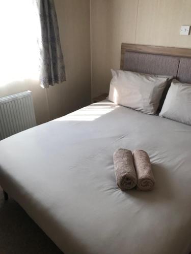 two towels sitting on a white bed with a window at Summer Breeze in Aviemore