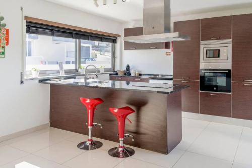 a kitchen with red stools in the middle of a counter at Casa Amour Villa in Lourinhã