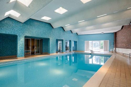 マンチェスターにあるBeautiful 'Mayfield' Villa with private pool!の青い壁の大型スイミングプール