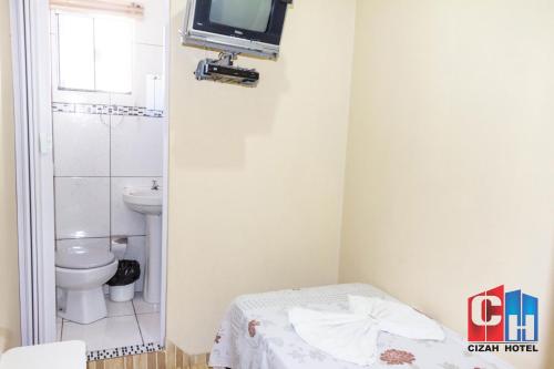 a bathroom with a toilet and a tv on the wall at Cizah Hotel in Faxinal