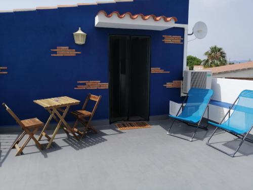 a patio with chairs and a blue wall at La Mongeta Màgica. in Castellón de la Plana