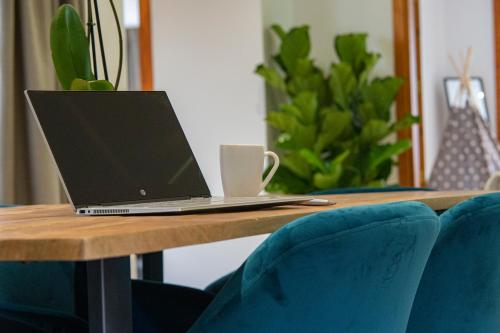 a laptop computer sitting on a wooden table with blue chairs at Laguna Home & Suites in La Laguna