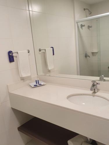 a white bathroom with a sink and a mirror at Summit Suítes Hotel Cachoeira Paulista in Cachoeira Paulista