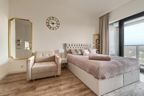1 dormitorio con 1 cama, 1 silla y 1 reloj en Apartament Hanza Tower 1412 en Szczecin