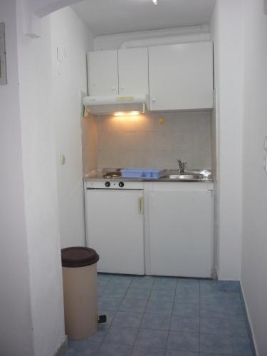 a small kitchen with white cabinets and a sink at Apanemia Rooms in Kini