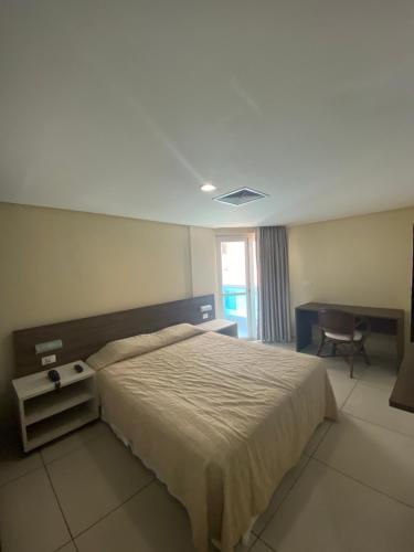 a bedroom with a bed and a desk and a chair at Imperial Suítes in João Pessoa