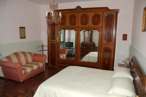 1 dormitorio con cama, silla y espejo en Villetta degli Ulivi, en Santa Rufina