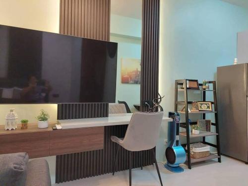 a living room with a large tv and a white chair at MOA Pasay, Shore 3 Residences - Modern Luxury Condo in Manila