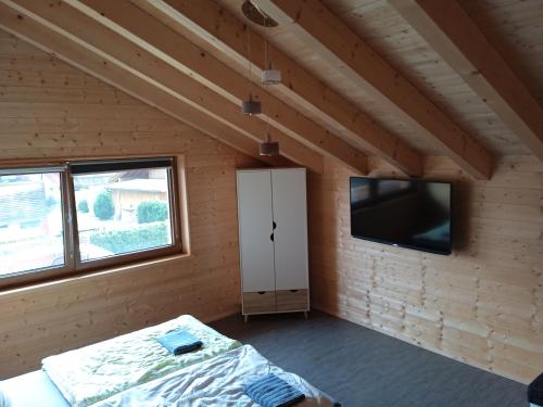 ein Schlafzimmer in einem Holzhaus mit einem Bett und einem TV in der Unterkunft Ferienwohnung Fernweh in Bolsterlang
