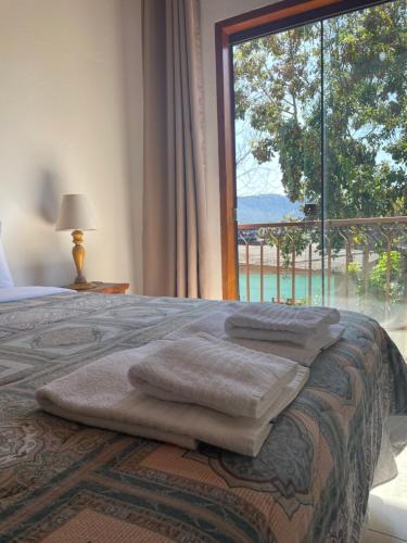 a bedroom with a bed with a large window at Sobrado Torre in Tiradentes