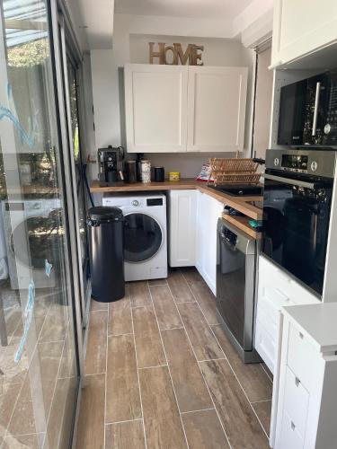 a kitchen with white cabinets and a washer and dryer at appart spa et mer in Bormes-les-Mimosas