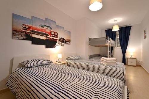 a bedroom with two beds and a picture of a car on the wall at Alojamiento Alcantara in Alora
