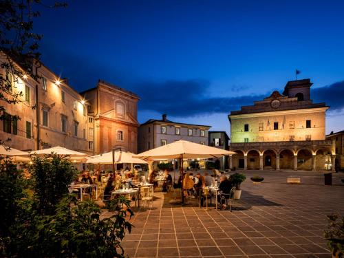 un grupo de personas sentadas en mesas bajo sombrillas en CivicoNove, en Montefalco