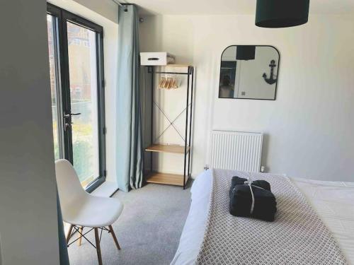 a bedroom with a bed and a chair and a mirror at Salt Yard Apartment, Parking and Terrace, Whitstable in Whitstable