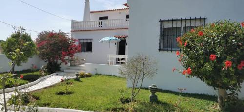 une maison blanche avec une cour fleurie dans l'établissement Vivenda Miraflores, à Armação de Pêra