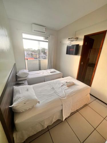 a hotel room with three beds and a window at Hotel Pinheiro in Ibiapina