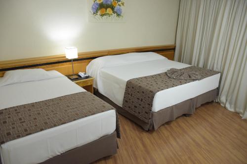 a hotel room with two beds and a lamp at Hotel Golden Park Internacional Foz & Convenções By Nacional Inn in Foz do Iguaçu