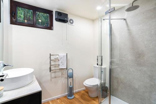 a bathroom with a shower and a sink and a toilet at Alpine Cottage in Queenstown