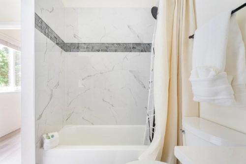 een witte badkamer met een douchegordijn en een bad bij Private Waterfront Retreat near downtown Auburn in Auburn