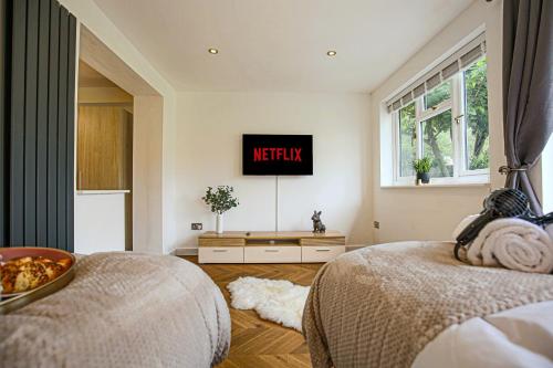 a bedroom with two beds and a tv on the wall at Central MK House - Sleeps Up To 9 Guests - Free Parking, Fast Wifi, Pool Table and Smart TV with Sky TV and Netflix by Yoko Property in Milton Keynes