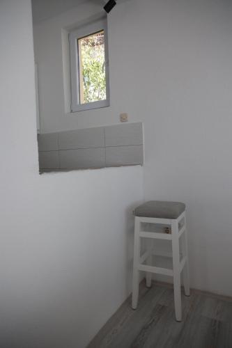 a white room with a stool and a window at Cavleski apartment in Prilep