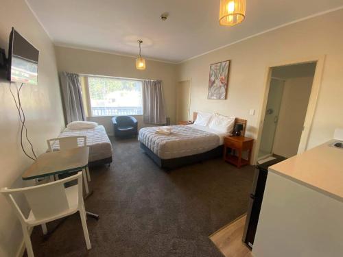 a hotel room with two beds and a desk and a table at Airport Westney Lodge in Auckland