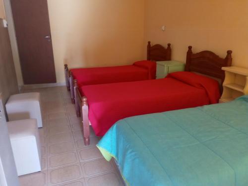 Habitación con 3 camas y sábanas rojas. en Casa Marques en Santa Rosa