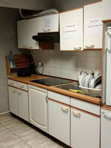 a kitchen with white cabinets and a stove top oven at Pokoje pod Świerkiem in Swarzędz