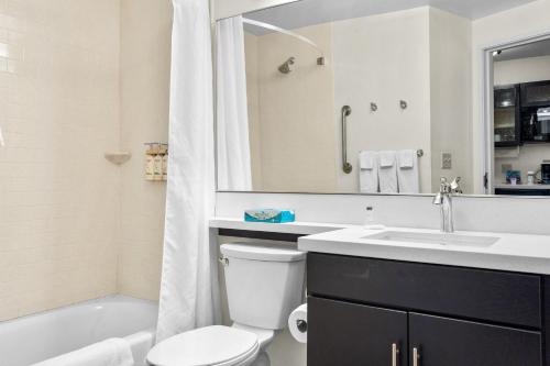 a bathroom with a toilet and a sink and a tub at Candlewood Suites Erie, an IHG Hotel in Erie
