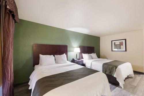 two beds in a hotel room with green walls at Quality Inn & Suites Terrell in Terrell