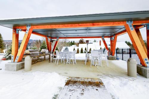 a covered patio with white chairs and a grill at All Season Mountain Retreat in Dover
