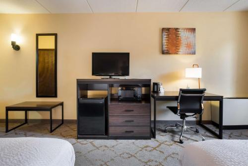 a hotel room with a bed and a desk and a television at Best Western Grand Victorian Inn in Sayre