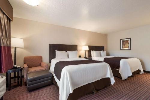 um quarto de hotel com duas camas e uma cadeira em Best Western Plus Cedar City em Cedar City