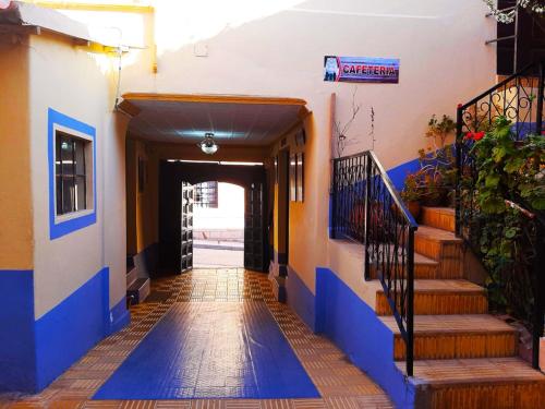 a hallway with blue and orange walls and stairs at Hostal Compañía de Jesús in Potosí