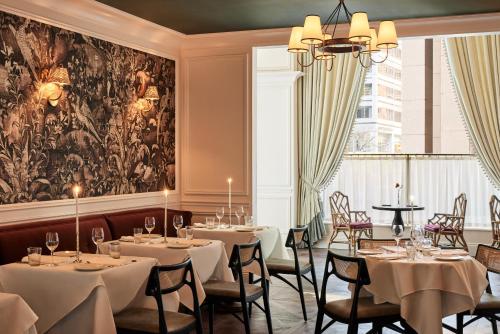 un restaurant avec des tables et des chaises et un grand tableau dans l'établissement The Wall Street Hotel New York City, à New York