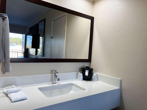 Un baño con lavabo y un espejo grande. en Motel 6 Hattiesburg, MS, en Hattiesburg
