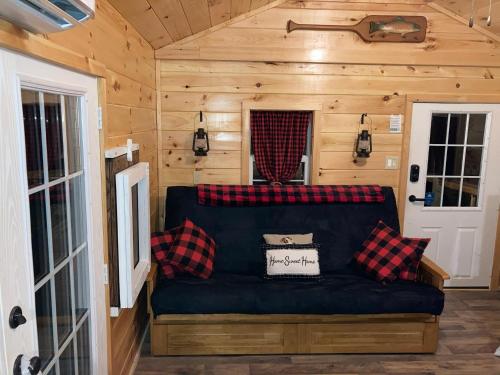 una sala de estar en una casa pequeña con sofá en Knotty Pines Cabin near Kentucky Lake, TN, en Springville