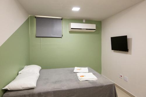 a small room with a bed with a tv and avertisement at Jahu Center Plaza Flats in Jaú