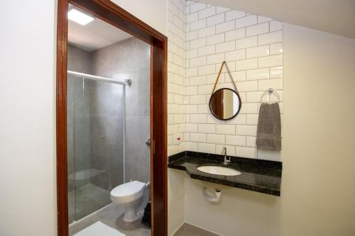 a bathroom with a toilet and a sink and a mirror at Jahu Center Plaza Flats in Jaú