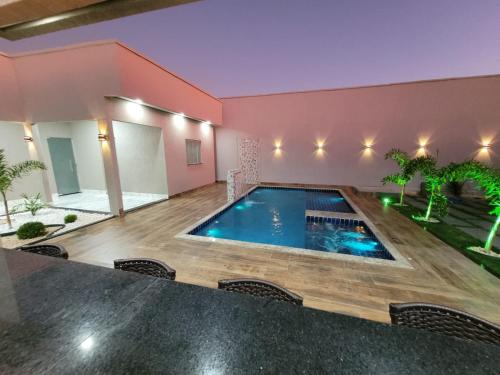 a swimming pool in a house with a pink wall at CASA ARUANÃ 5 SUITES in Aruanã